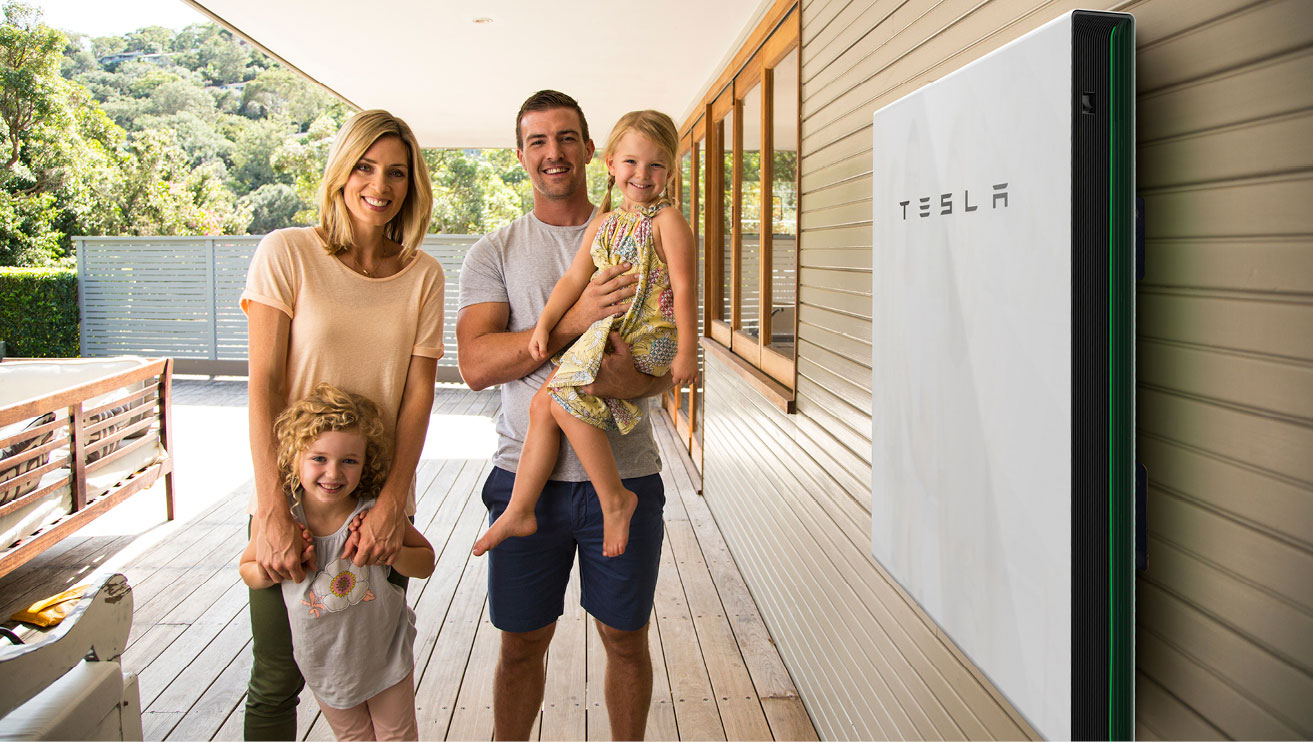 Family with two kids standing next to Tesla Powerwall